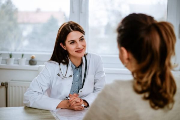 Cheerful young doctor listening to a patient in the office. Cheerful young doctor listening to a patient in the office.